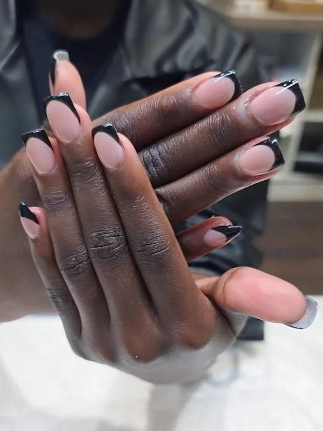 Mujer en un salón de uñas mostrando su manicura BIAB en tono nude con extensiones negras
