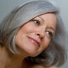 Primer plano de una mujer con un bob gris liso y maquillaje natural