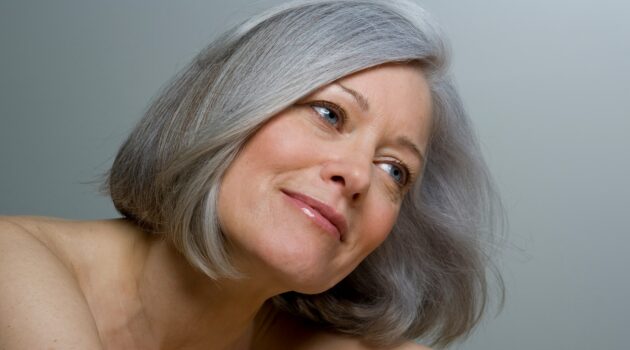 Primer plano de una mujer con un bob gris liso y maquillaje natural