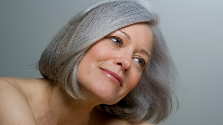 Primer plano de una mujer con un bob gris liso y maquillaje natural