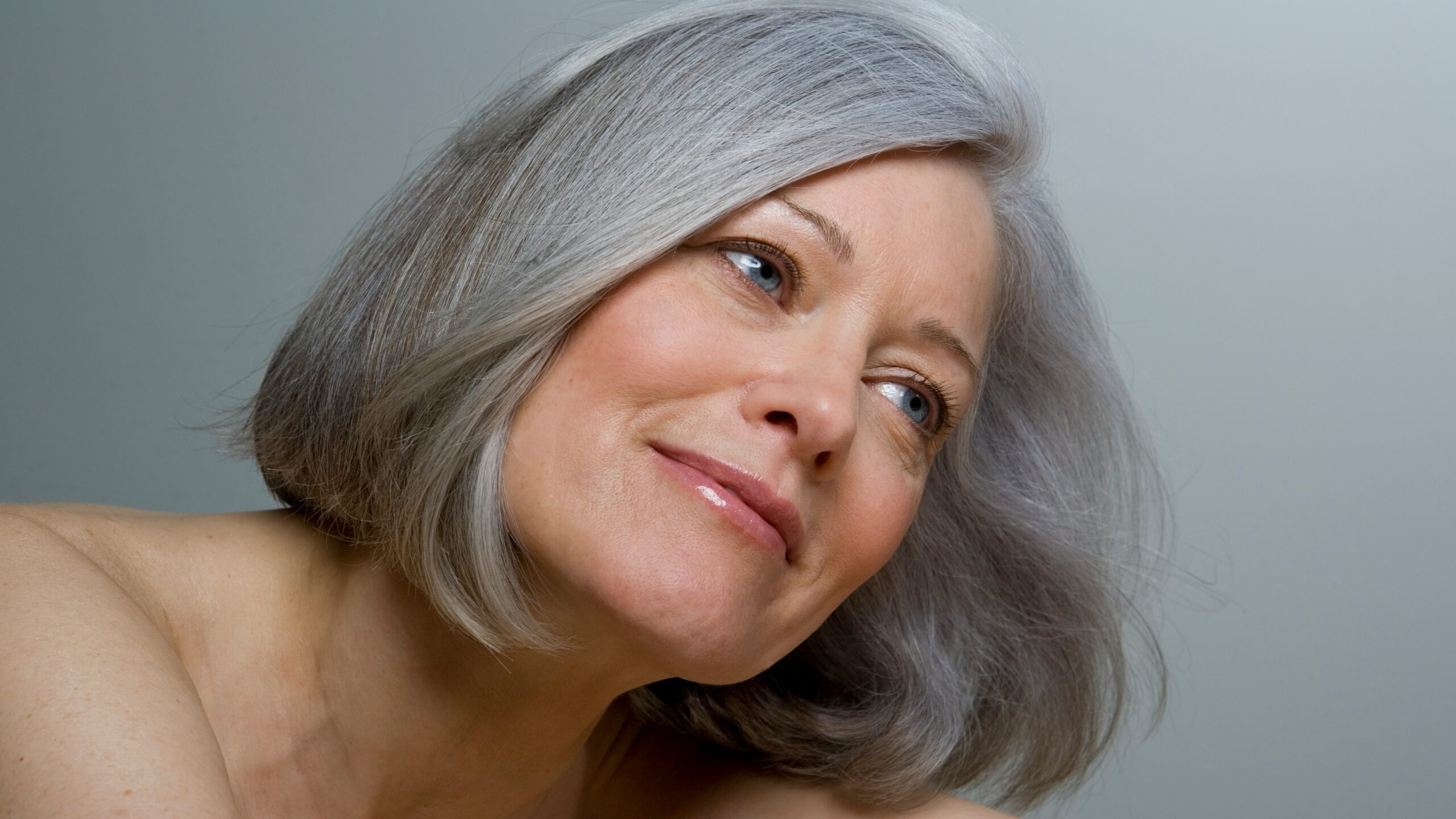 Primer plano de una mujer con un bob gris liso y maquillaje natural