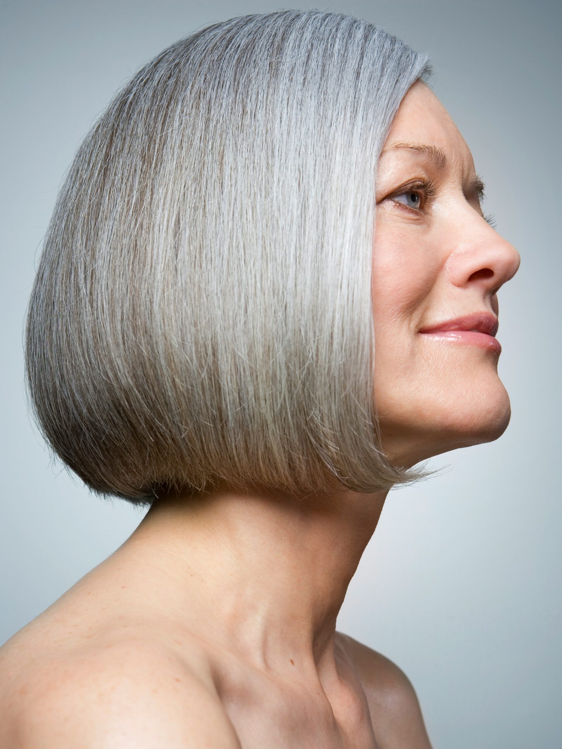 Retrato de perfil de una mujer con un bob gris sano y brillante