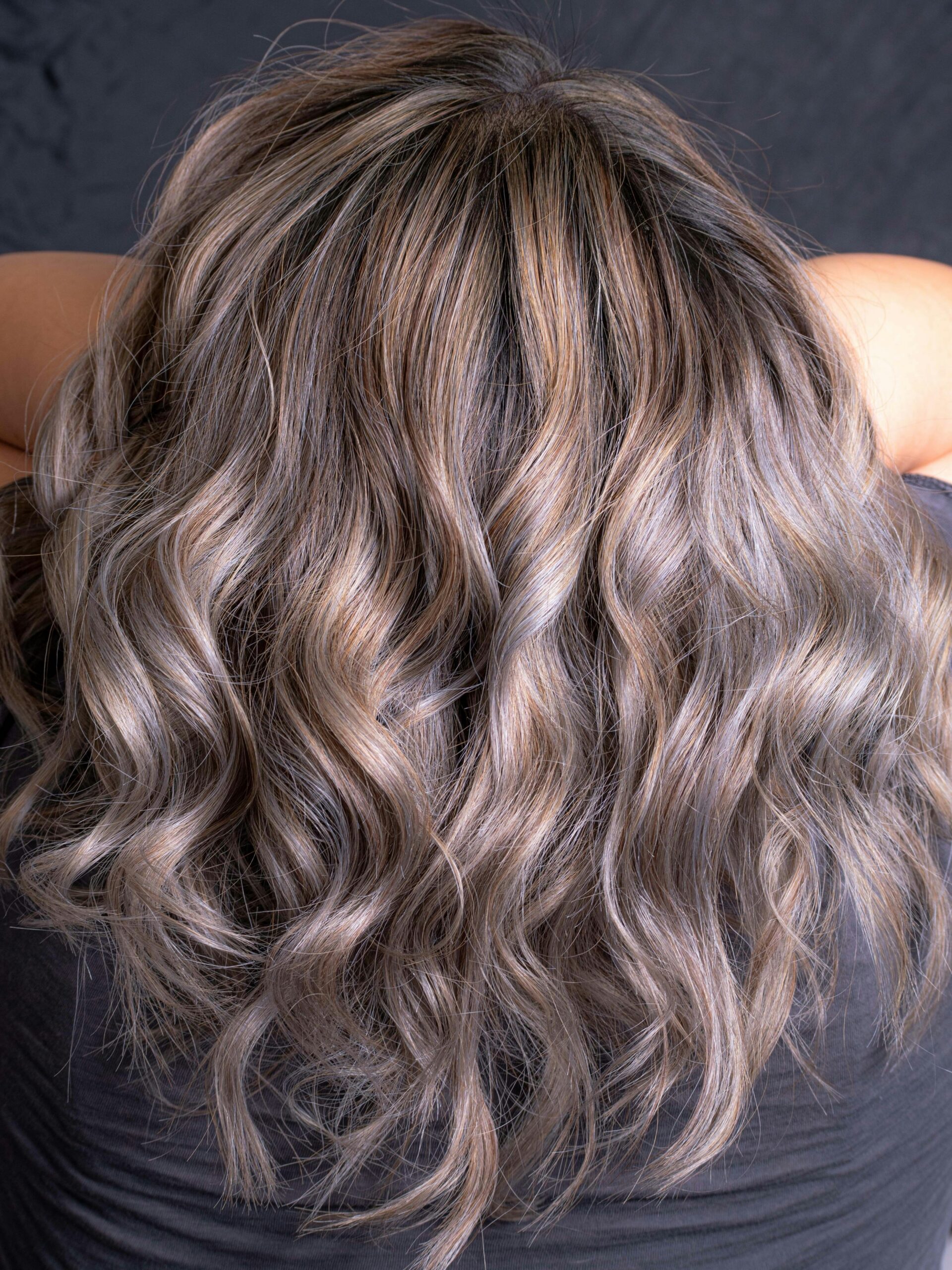 Parte trasera de la cabeza de una mujer mostrando cabello ondulado con canas difuminadas