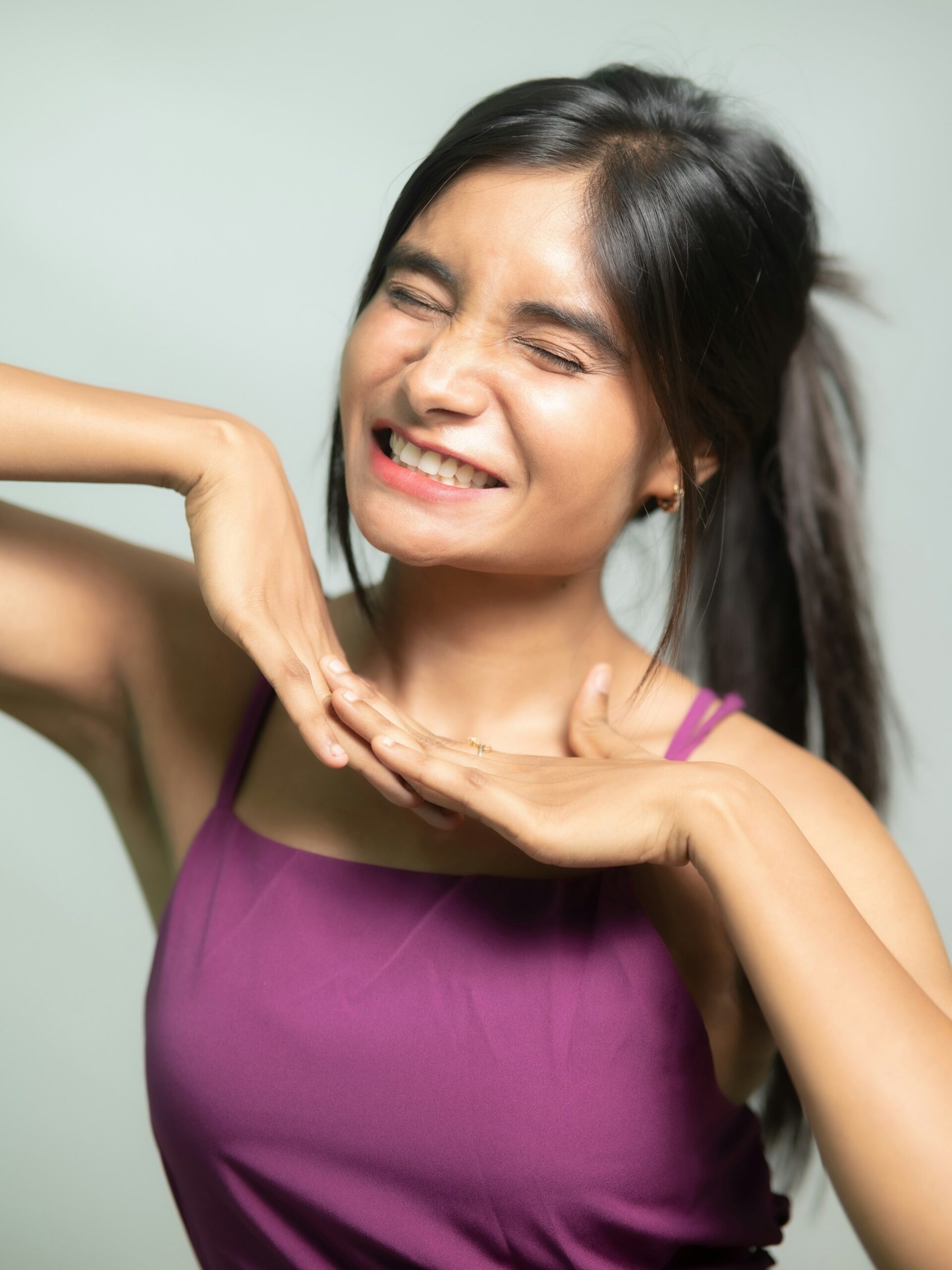 Mujer con piel clara y pelo oscuro sonriendo con una camiseta de tirantes morada