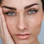 Primer plano del rostro de una mujer con microblading en las cejas, maquillaje natural y el pelo oscuro recogido
