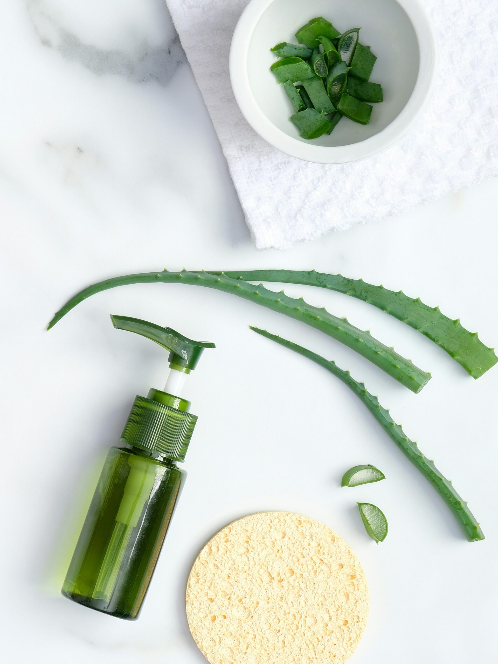 Flat lay de un producto calmante de aloe vera para el cuidado de la piel, con aloe vera natural y una esponja