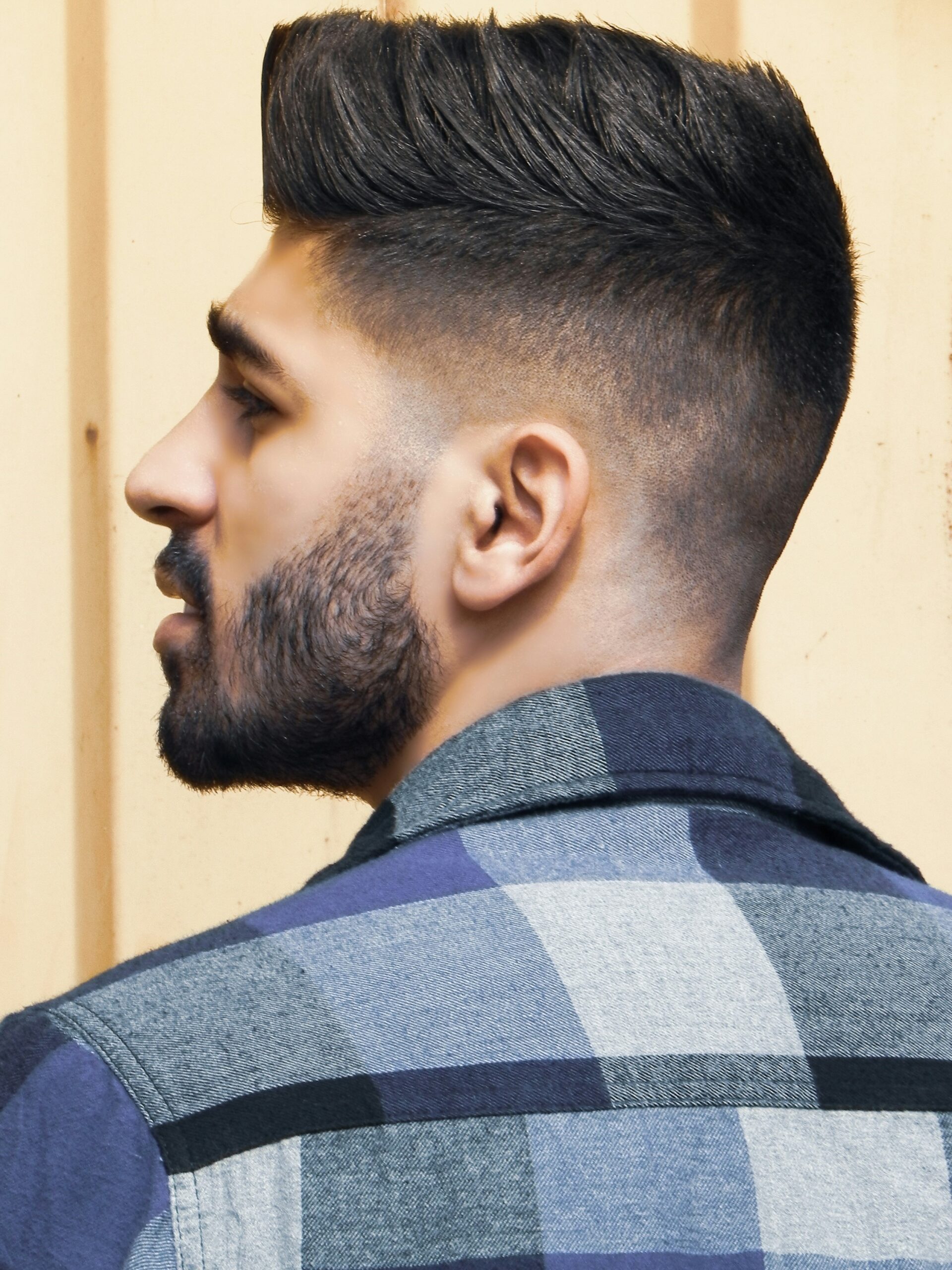 Retrato de perfil de un hombre con un peinado tipo cresta (faux hawk) combinado con un high taper fade