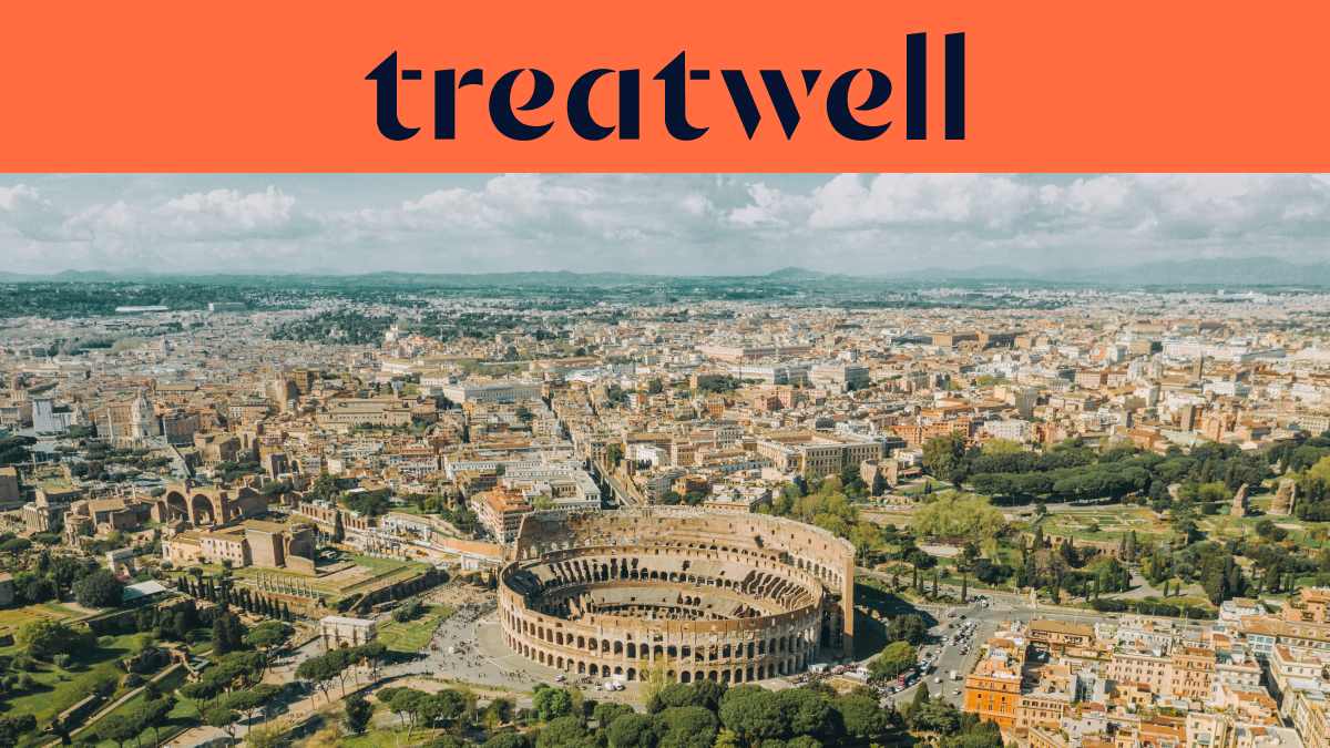 Vista aérea de Roma con el icónico Coliseo en primer plano. La ciudad histórica se extiende hacia el horizonte bajo un cielo nublado. Un gran banner naranja en la parte superior muestra el logotipo de Treatwell.