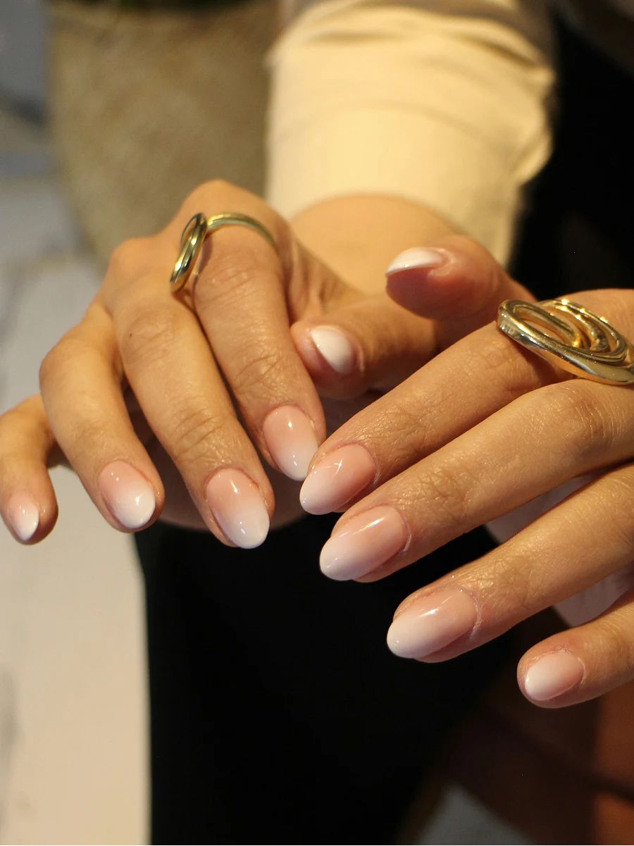 Primer plano de la manicura Shellac en degradado de una clienta, en tonos nude clásicos, recién hecha en el salón