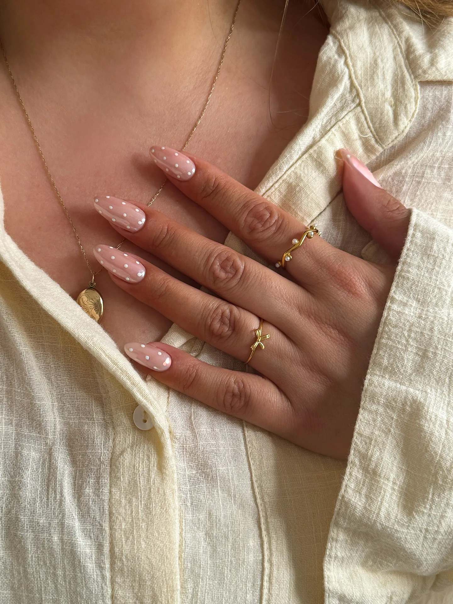 Uñas almendradas sobre base rosa transparente, salpicadas de mini lunares blancos repartidos de forma uniforme.