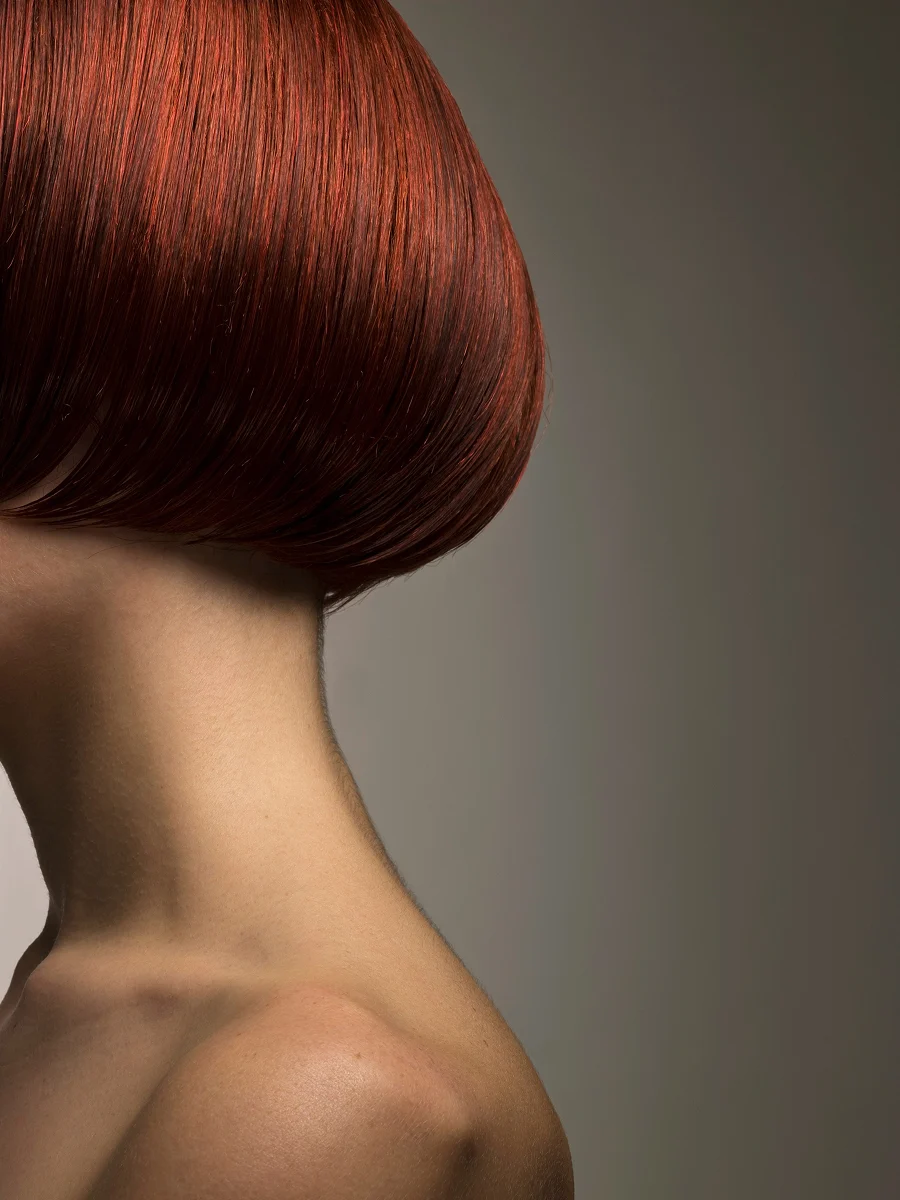 Primer plano de perfil de la cabeza de una mujer con un bob teñido de rojo y muy brillante