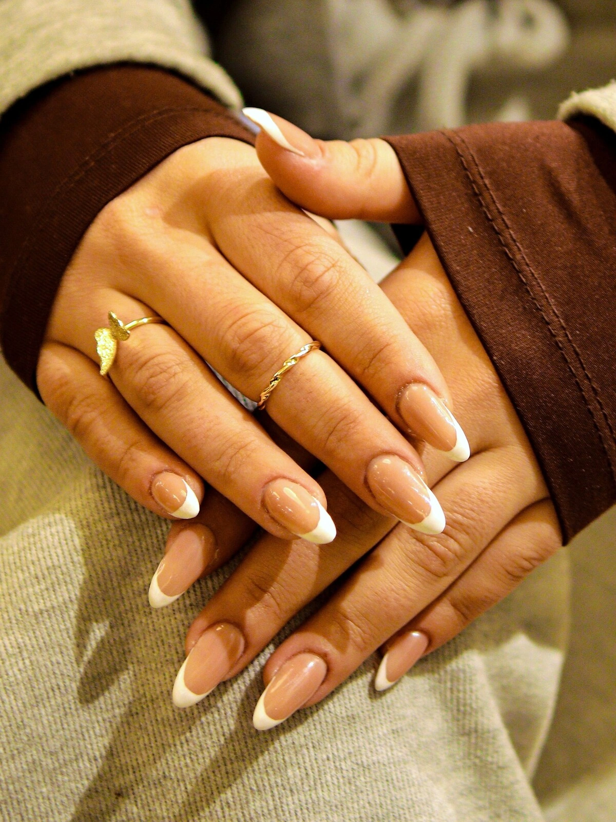 Las manos de una mujer con una llamativa manicura francesa en una combinación de beige y blanco sobre uñas largas de almendra