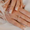 Manicura francesa clásica en blanco sobre uñas naturales de forma cuadrada, sobre una tela blanca