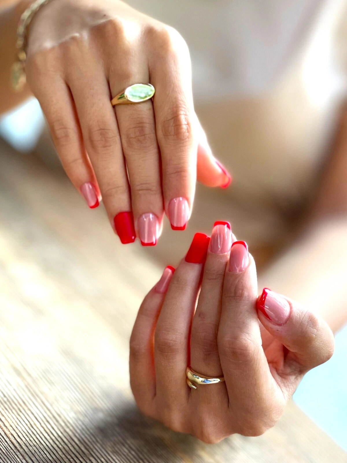 Una manicura francesa sobre uñas cuadradas-ovaladas con base rosa claro y puntas rojas, y los anulares por completo en rojo