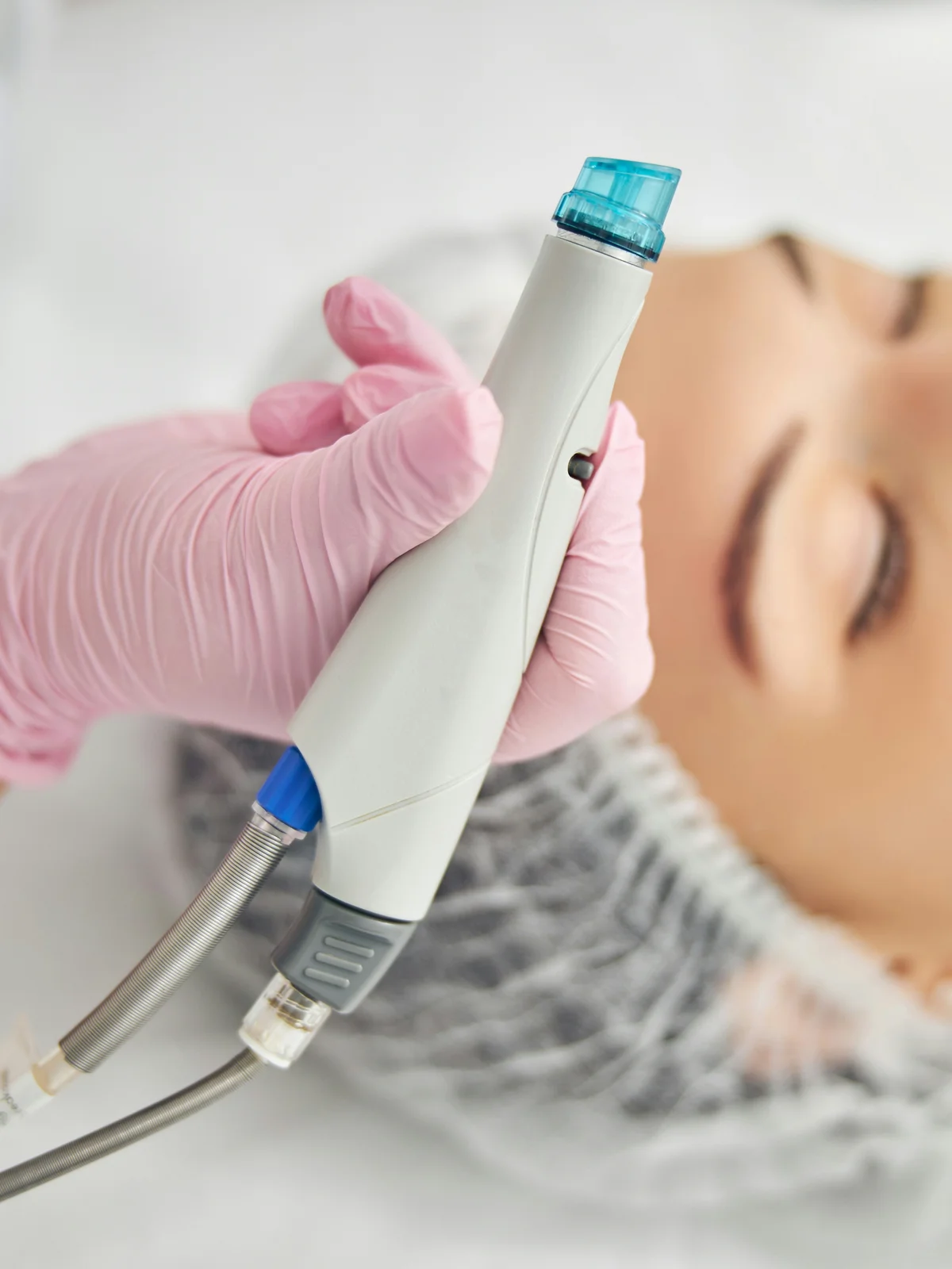 Primer plano de un dispositivo HydraFacial con cabezal en espiral sostenido por una especialista