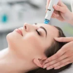 Primer plano de una mujer relajada con los ojos cerrados durante un tratamiento HydraFacial en un centro tranquilo