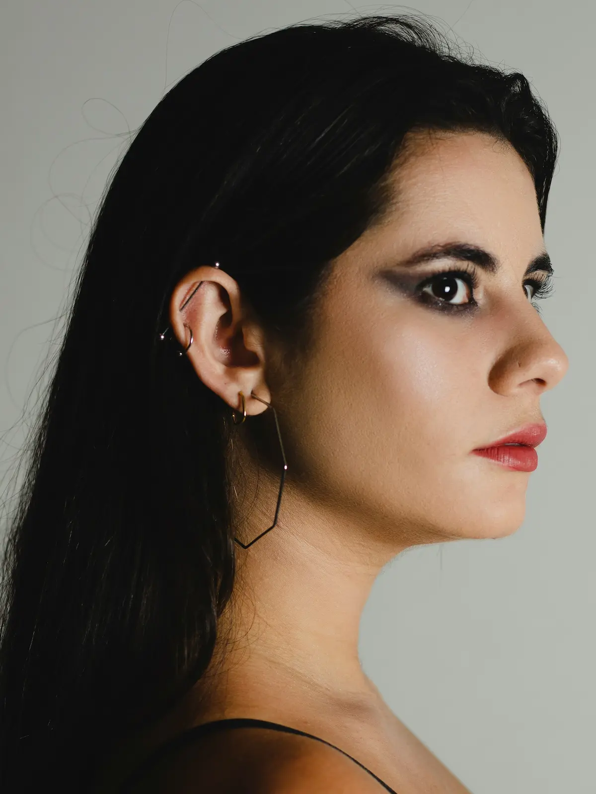 Foto de estudio de una mujer con una barra industrial y piercings en el lóbulo y el hélix