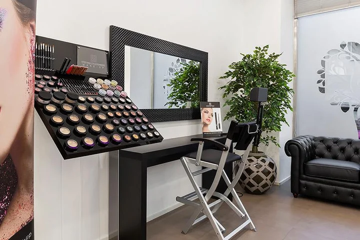 Luminoso salón de manicura Top Estetica en Villanova, Cagliari, con pared turquesa, mesas florales y suelos de mármol.