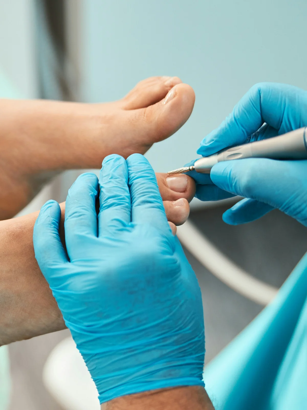 Primer plano de una esteticista con guante que perfila las cutículas de los dedos del pie de una clienta con una herramienta pequeña