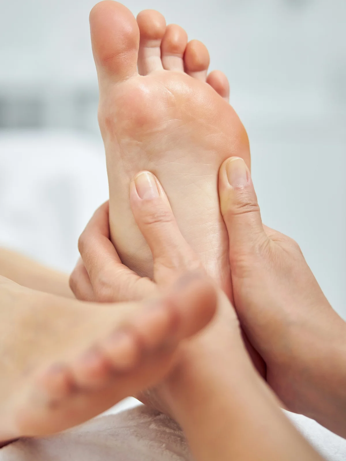 Primer plano de una esteticista masajeando el pie de una clienta durante una pedicura en seco
