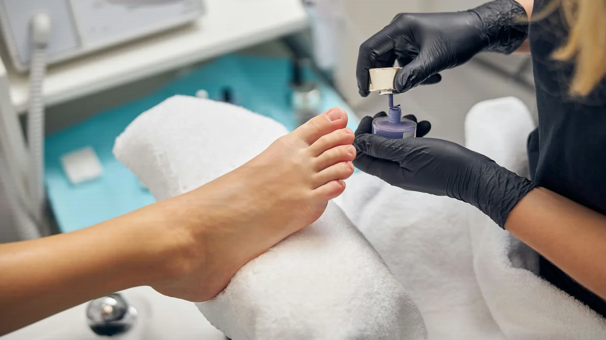Primer plano de una manicurista haciéndole la pedicura a una clienta en el centro
