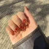 Uñas lava nails con remolinos ámbar y rojos sobre base transparente